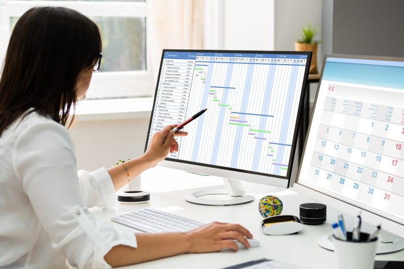 A woman reviewing a schedule on her monitor